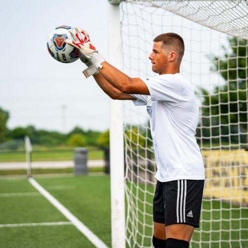 Goalkeeper making a catch while wearing Fleur De Lis GK Nova Pro OG University Red Trim.