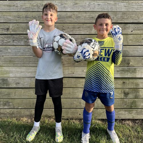 Two (2) youth goalkeepers showing off their Fleur De Lis GK Nova Pro OGs.